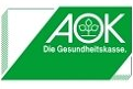 AOK Krankenversicherungen logo: Three dimensional rectangle box with diagonal green band and white AOK logo which consists of the AOK acronym with a three leaf plant graphic in the O stacked on top of a line that reads 'Die Gesundheitskasse'.