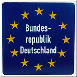 European flag (circle of yellow stars on dark blue background) with 'Bundes-republik Deutschland' stacked on three lines in white letters in the center of the circle on hte flag